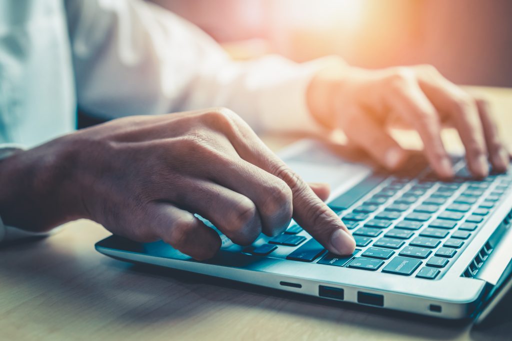 Businessman hand typing on computer keyboard of a laptop computer in office. Business and finance concept.